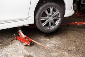 A car jack underneath a vehicle to assist in holding it up