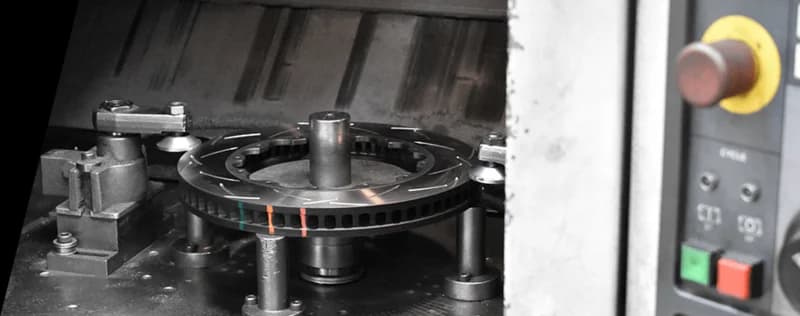 DBA high-precision manufacturing process showing brake rotor with thermal paint indicators during production DBA brake rotor with colored temperature indicators being manufactured on precision CNC machine with control panel visible in background