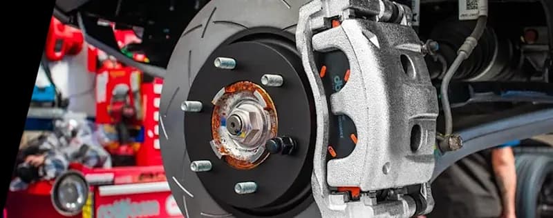 High-performance DBA brake system installation featuring slotted rotor and caliper components Performance brake system close-up showing DBA slotted rotor installed on vehicle with silver caliper and visible hub assembly